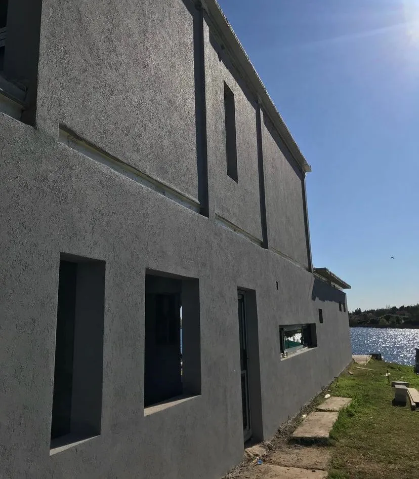 Fachada con revestimiento texturado gris en construcción frente al agua